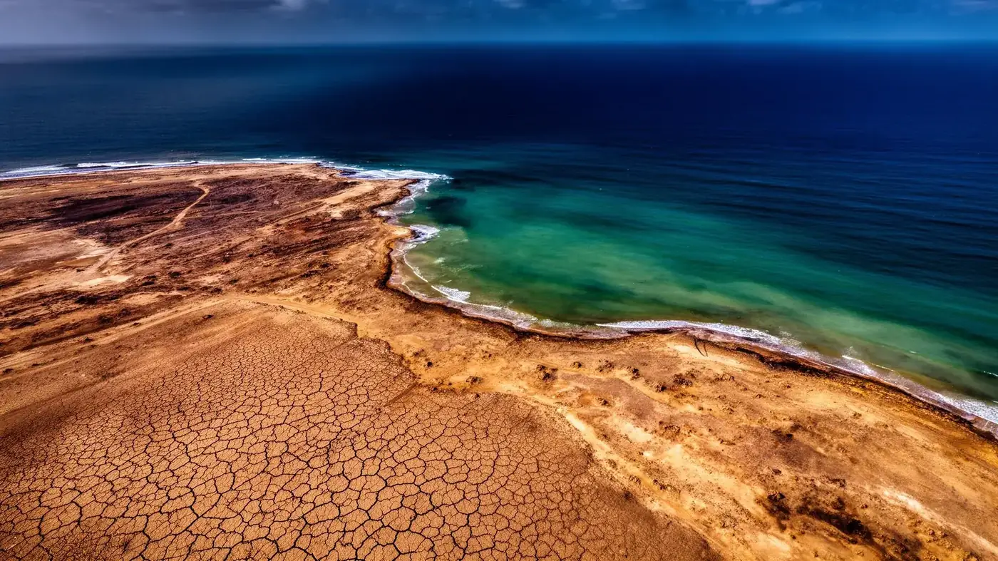 Aerial view of degraded arid coastal land meeting deep blue ocean
